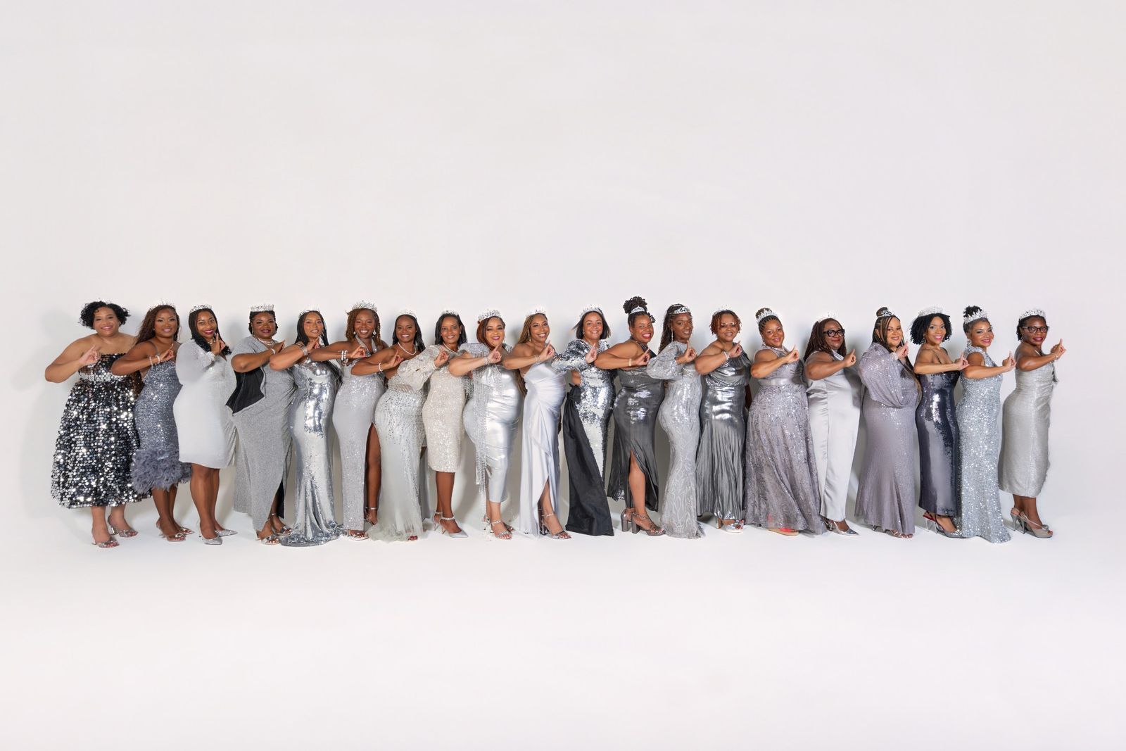 Full chapter line in silver gowns and tiaras, studio backdrop